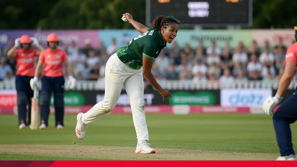 Close sideline action of a women's batter driving through the off side under stadium lights